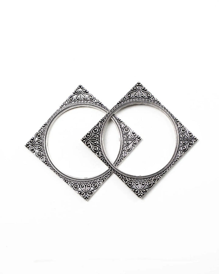 Pair of square oxidised silver bangles with intricate designs on a white background