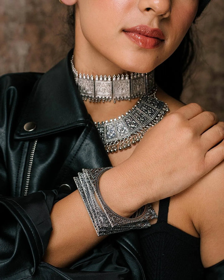 Person wearing a silver necklace and oxidised square silver bangles